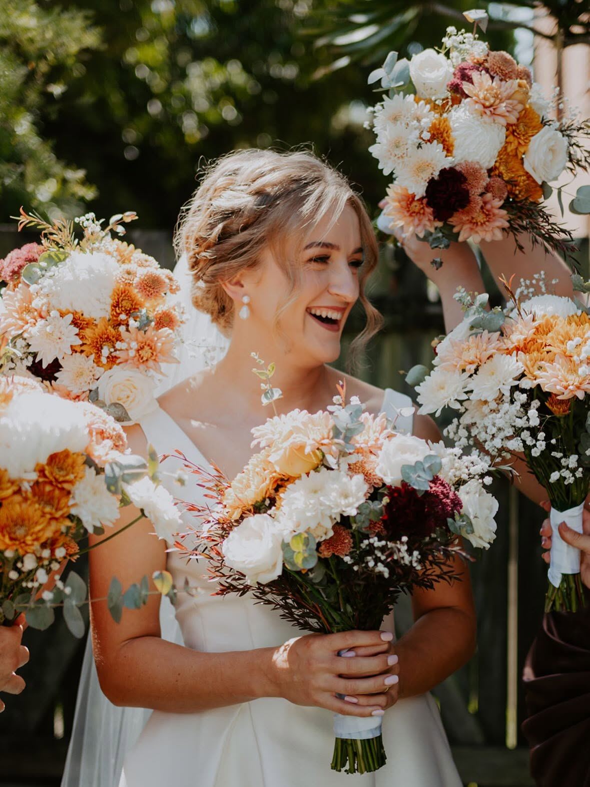 Bride laughing among orange and white wedding bouquets