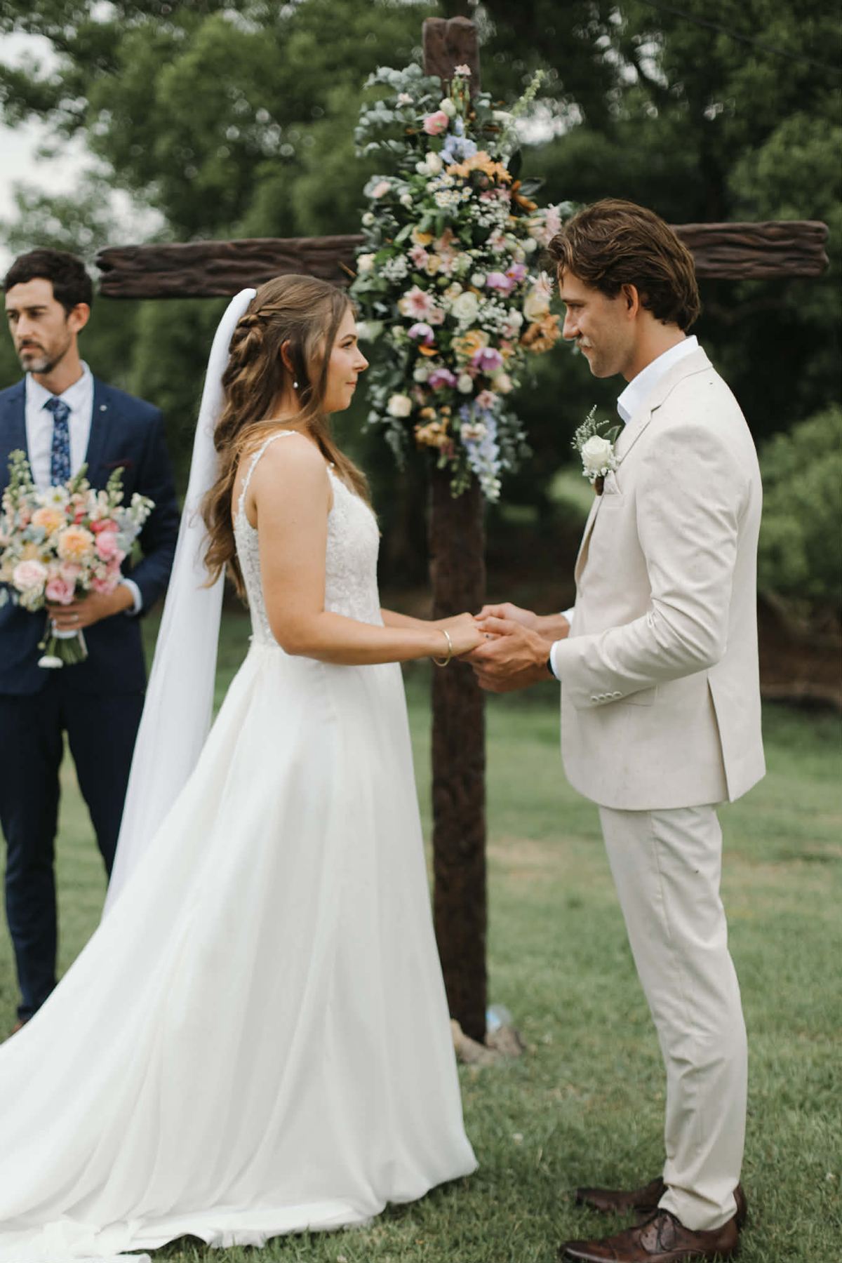 Bride and groom holding hands at the altar with a floral-covered cross