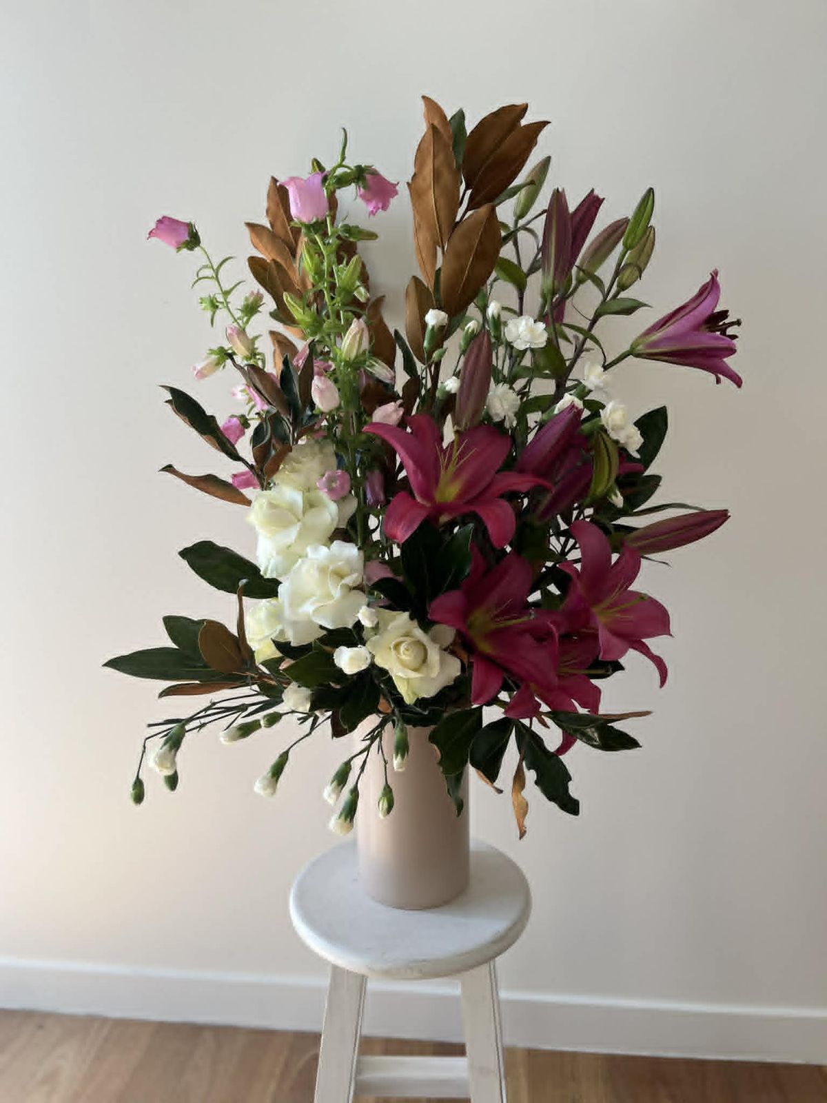 Lily and rose arrangement in a vase on a stool