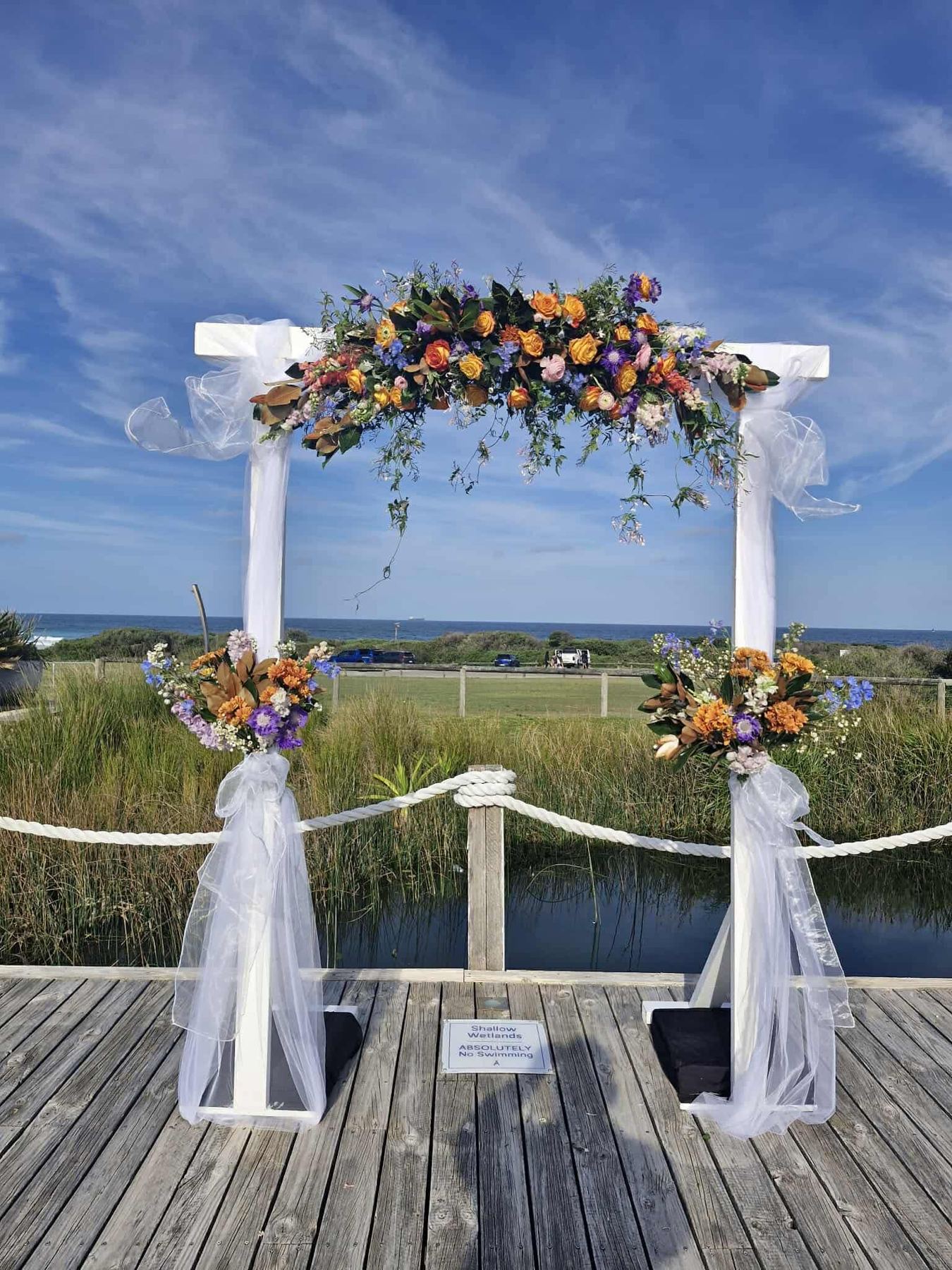 Floral ceremony arch overlooking wetlands and the ocean